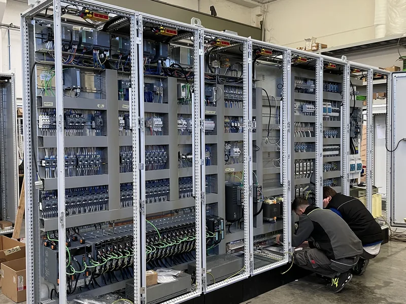 Tecnici al lavoro su un quadro elettrico a più colonne