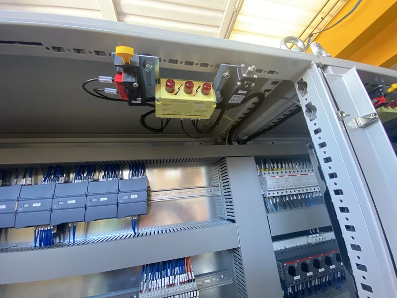 Parte alta del quadro con i moduli del PLC e una pulsantiera gialla