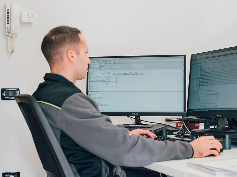 Programmatore Tecno10 al lavoro su due monitor con il software del PLC