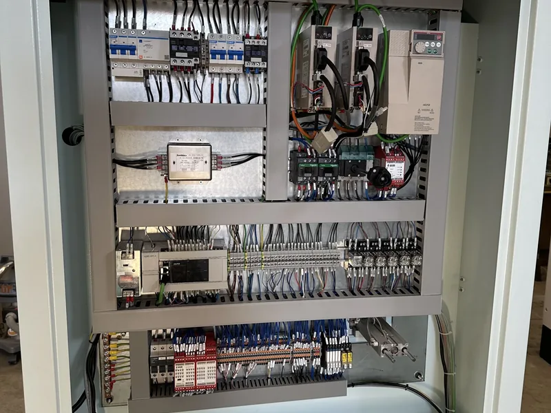 Quadro elettrico aperto: inverter, moduli di sicurezza rossi e morsettiere