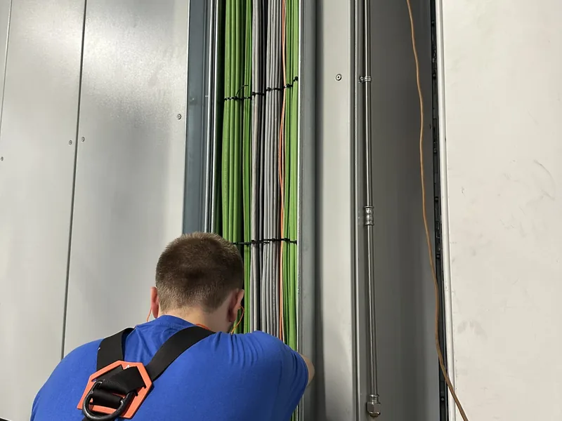 Tecnico Tecno10 che fissa i cavi lungo la canalina verticale di un quadro elettrico