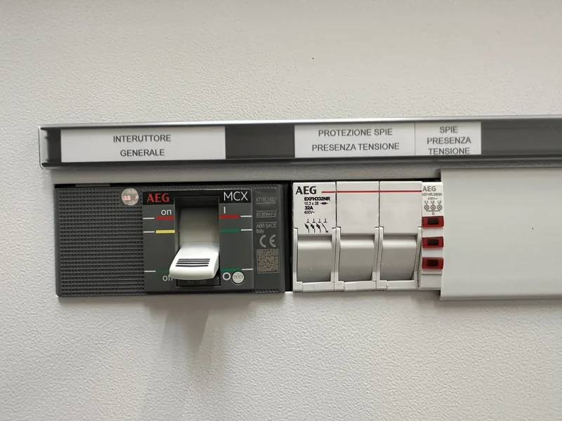Interruttore generale scatolato AEG sul fronte del quadro generale, accanto alle protezioni delle spie di presenza tensione